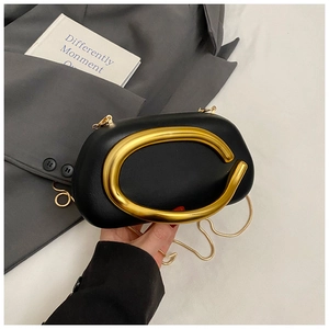 Detail of black acrylic clutch with gold circular handle and crossbody chain