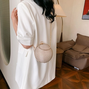 Sac sphérique doré champagne avec paillettes et poignée diamantée sur blazer blanc chic