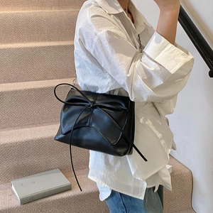 Minimalist black PU leather shoulder bag with a stylish bow tie decor on a white shirt model