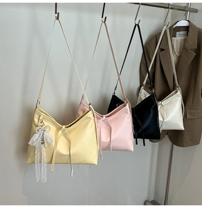 Detail of minimalist tote bags in yellow, pink, black and white with lace bow pendants