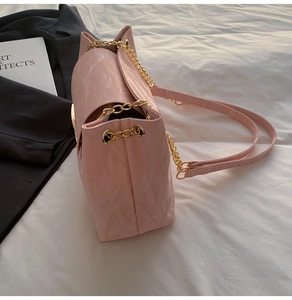 Detail der rosa Plissee-Tasche mit goldener Kette und glänzenden runden Beschlägen