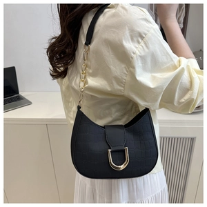 Detail of crocodile pattern black crescent bag with golden horseshoe buckle and strap