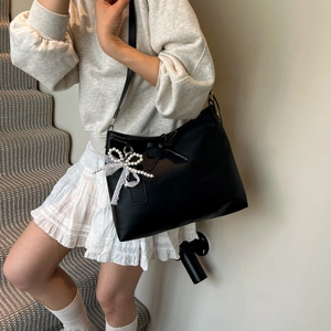 Black leather tote bag with pearl bow and lace detail shown on model in stair setting