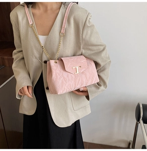 Detail der rosa Leder-Schultertasche mit Metall-T-Logo und eleganter Kettenriemen-Optik