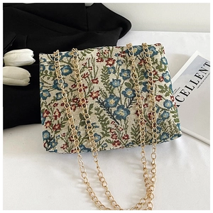 Detail of vintage floral jacquard fabric and gold chain strap on small crossbody bag