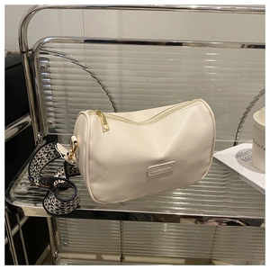 Detail of off-white leather pillow bag featuring a woven strap and gold zipper hardware