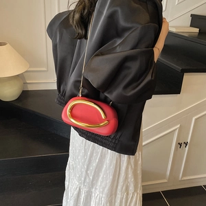 Elegant red square chain bag with bold gold metal buckle shown in a minimalist room