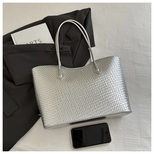 Detailed view of silver tote bag with textured woven pattern and elegant top handles