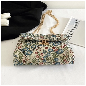 Detailed close-up of floral print crossbody bag with gold chain strap and square metal lock