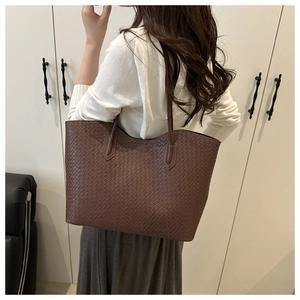 Detail of dark brown woven leather tote bag shown from a back perspective on a model