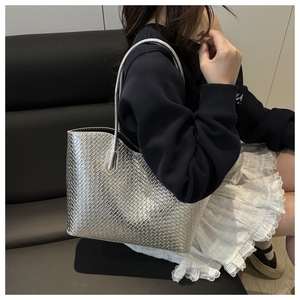 Detailed close-up of metallic silver woven tote bag featuring intricate cross-weave texture