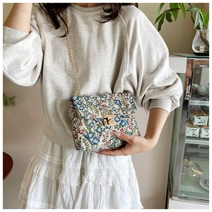 Detail of floral embroidery on a vintage crossbody bag with a gold metal twist lock