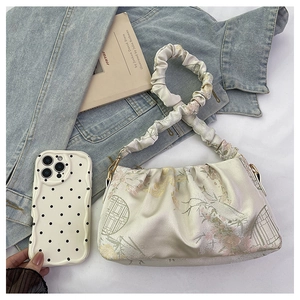 Détail du sac à bandoulière plissé beige à motifs floraux et coque de téléphone à pois