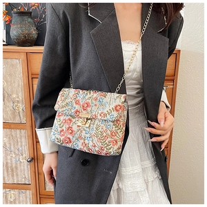 Detail of floral tapestry crossbody bag with gold chain and metal twist lock closure