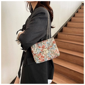Detail of floral embroidery on a vintage cream crossbody bag with gold chain strap