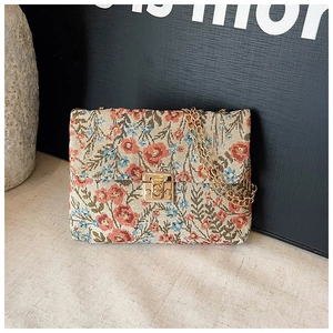 Detailed view of floral tapestry fabric with vintage golden metal buckle and chain strap
