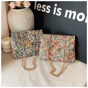 Detail of vintage floral jacquard crossbody bags with golden chain straps and clasps