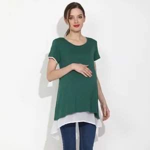 Detail of loose maternity top featuring dark green fabric and white chiffon hemline split
