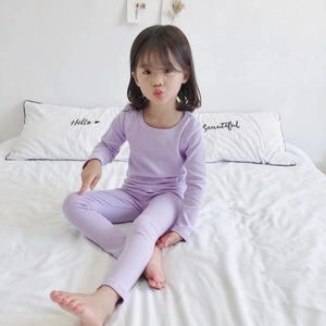 Kids purple cotton thermal pajama set with long sleeve top and pants on a white bed