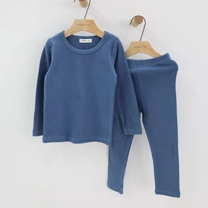 Detail view of smog blue cotton pajama set for kids hanging on a wooden hanger