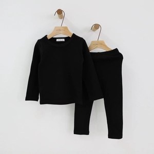 Detail view of black long-sleeve thermal kids' sleepwear set on a wooden hanger