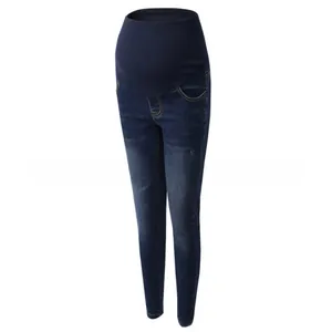 Detail of dark blue maternity slim jeans featuring whiskers and washed denim finish
