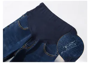 Detailed close-up of dark blue maternity jeans featuring elastic belly support and stitching