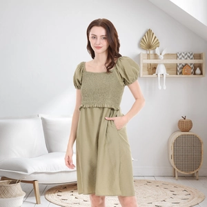 Sage green maternity dress with smocked bodice, puff sleeves, and functional pockets