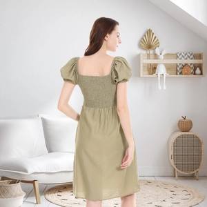 Detail view of the smocked back and puff sleeves on a light olive green maternity dress
