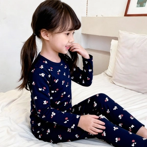 Pyjama enfant bleu marine en coton à motifs de nœuds rouges sur un lit blanc douillet