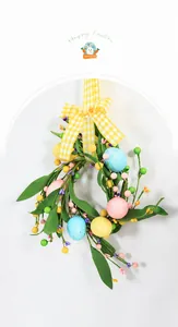 Detail of Easter wreath with colorful eggs, green leaves, and a yellow plaid bow