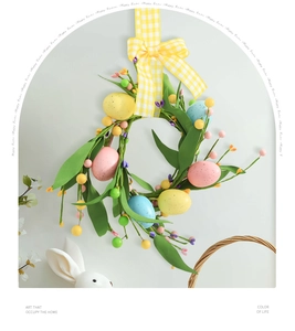 Detail of Easter egg wreath with green leaves and a yellow checkered bow on gray background