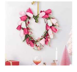 Detail of heart-shaped tulip wreath with red and pink silk flowers on a white wall
