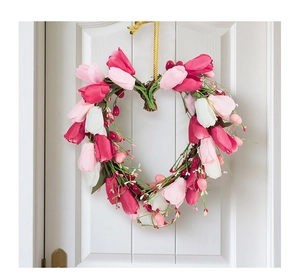 Detail of heart-shaped tulip wreath with pink berries on a white wooden door