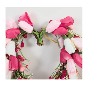 Detail of heart-shaped tulip wreath with pink blossoms and red berries on rattan base