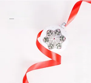 Detailed view of a white Christmas ball ornament with snowflake print and red ribbon