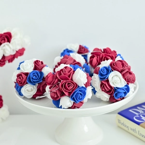 Close-up of red white and blue foam rose poms with hanging ribbons for party decor