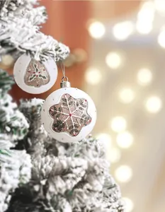 Close-up of white hand-painted Christmas balls with glittery snowflakes on pine branch