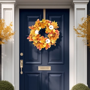 Fall wreath with maple leaves and pumpkins hanging on a deep blue door decoration