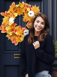 Close-up of autumn wreath with maple leaves and pumpkins on a dark blue wooden door