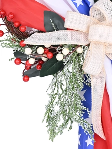 Close-up of USA flag berry wreath featuring rustic beige burlap bow and green foliage