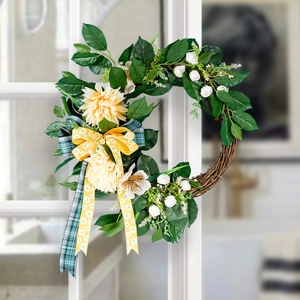 Detail of handcrafted Christmas wreath with cream dahlias and green leaves on vine base