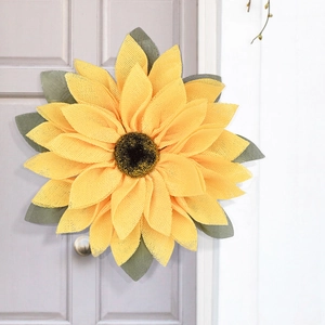 Detail of sunflower mesh wreath with yellow petals and green leaves for home wall decor