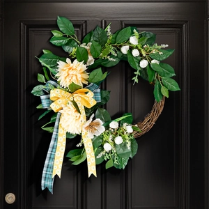 Detail of handmade Christmas wreath with yellow dahlia flowers and daisy ribbon on door