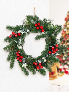 Detail of pine needle Christmas wreath with red berries hanging on a white wall