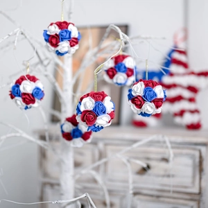 Patriotic red white and blue rose flower ball ornaments hanging on a white decorative tree
