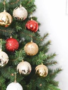 Close-up of red and gold glitter Christmas balls hanging on a pine tree branch