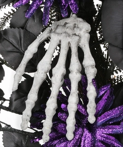 Detail of Halloween wreath with skeleton hand, purple glitter flowers and black leaves
