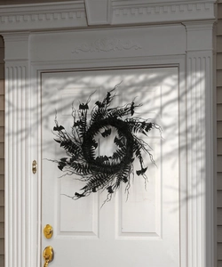 Detail view of a black Halloween wreath with bats and glitter on a white wooden door
