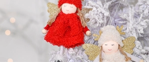 Dettaglio di angeli natalizi in peluche con ali dorate su un ramo di albero innevato